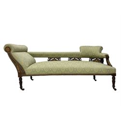 Late Victorian walnut salon settee or chaise lounge, double-ended with rolled back and curved end, upholstered in light aquamarine fabric with raised repeating lozenge pattern, decorated with laurel leaf wreaths and urns, three pierced splats carved with curled leaves, inlaid with dolphins and scrolled foliate motifs in simulated ivory and boxwood, on tapering ring turned supports with brass and ceramic castors (L166, D60, H70cm); together with matching tub-shaped armchair (W61cm, H73cm, D66cm)  