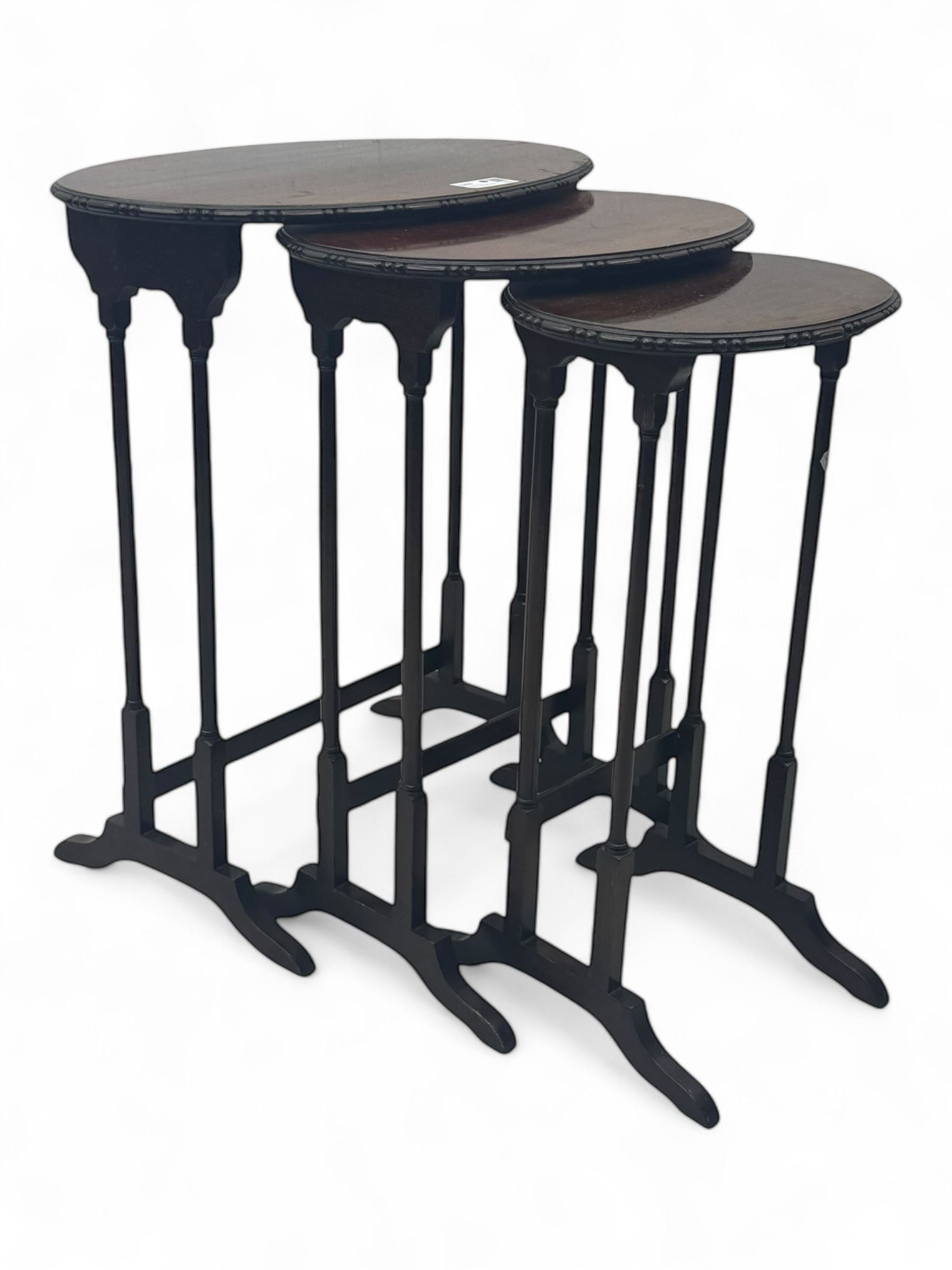 Early 20th century mahogany nest of three tables, oval tops with carved edges, turned uprights with splayed feet united by cross stretchers