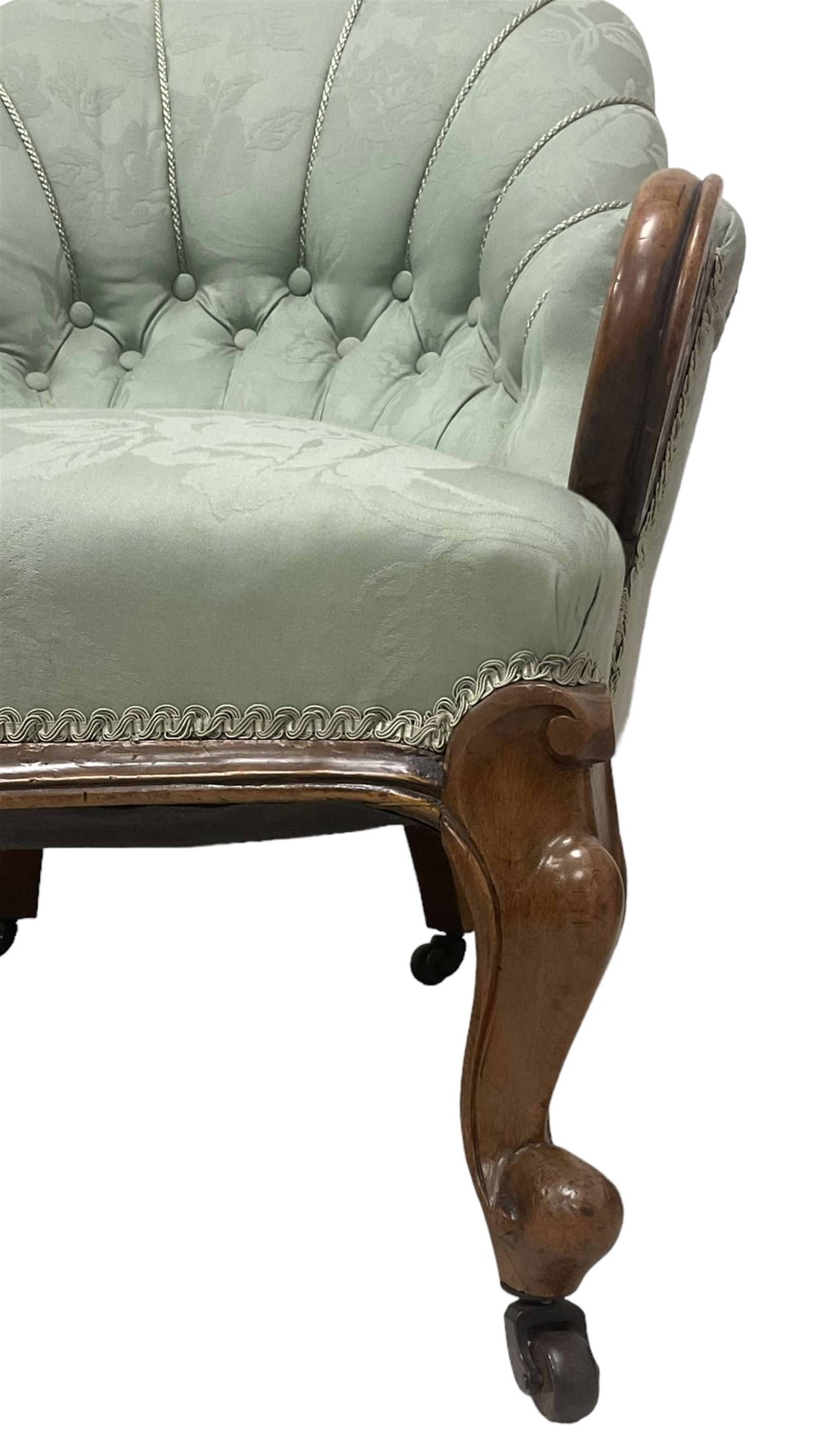 19th century mahogany framed fan-back armchair, upholstered in buttoned turquoise floral damask fabric with spring seat and pearlescent piping, pierced and carved arm terminals with floral motif, over serpentine fronted seat, raised on cartouche carved cabriole supports with castors