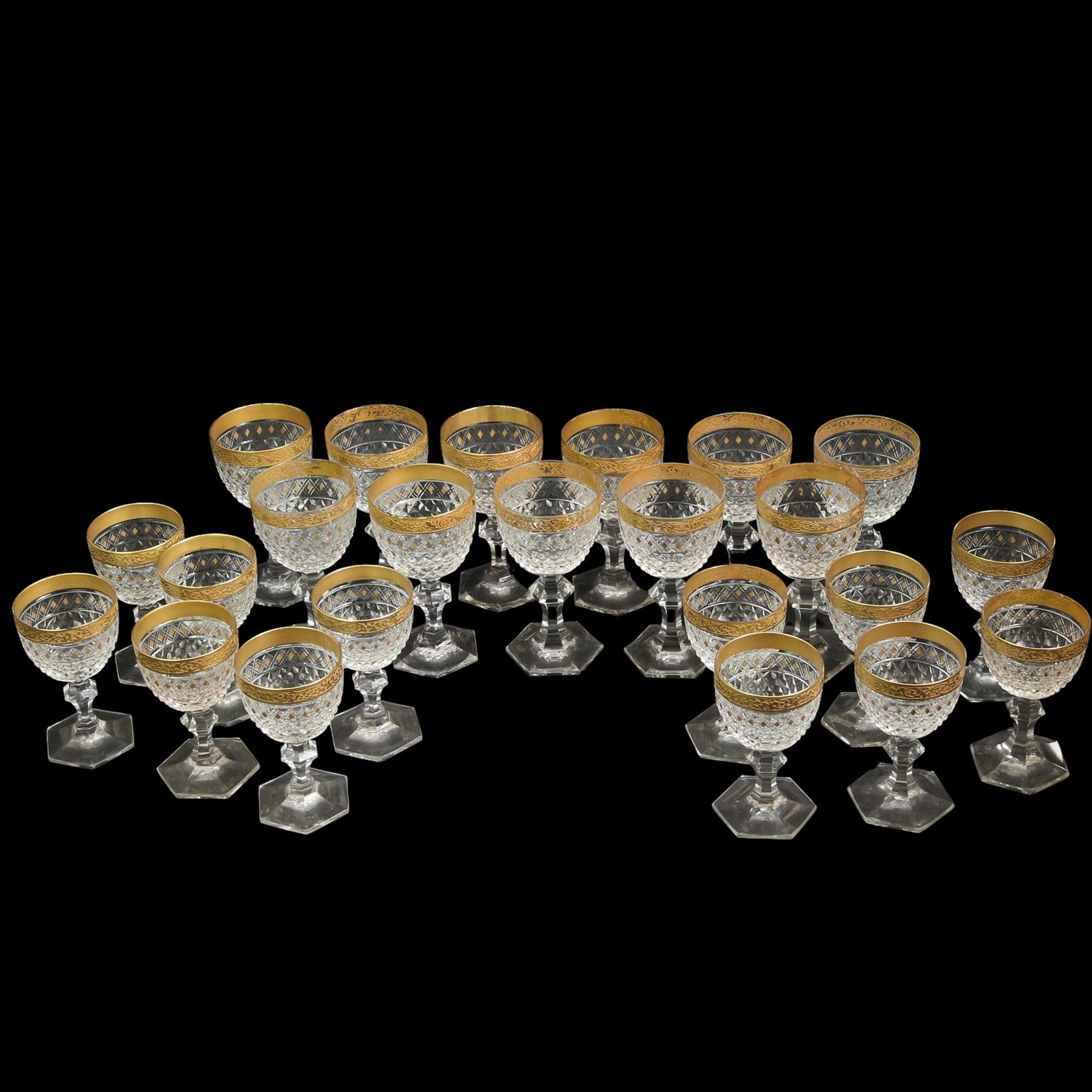 Part suite of crystal drinking glasses comprising thirteen red wine glasses and twelve white wine glasses, all with foliate gilt banding, hobnail cut bowls and hexagonal faceted stems, in the style of Moser 