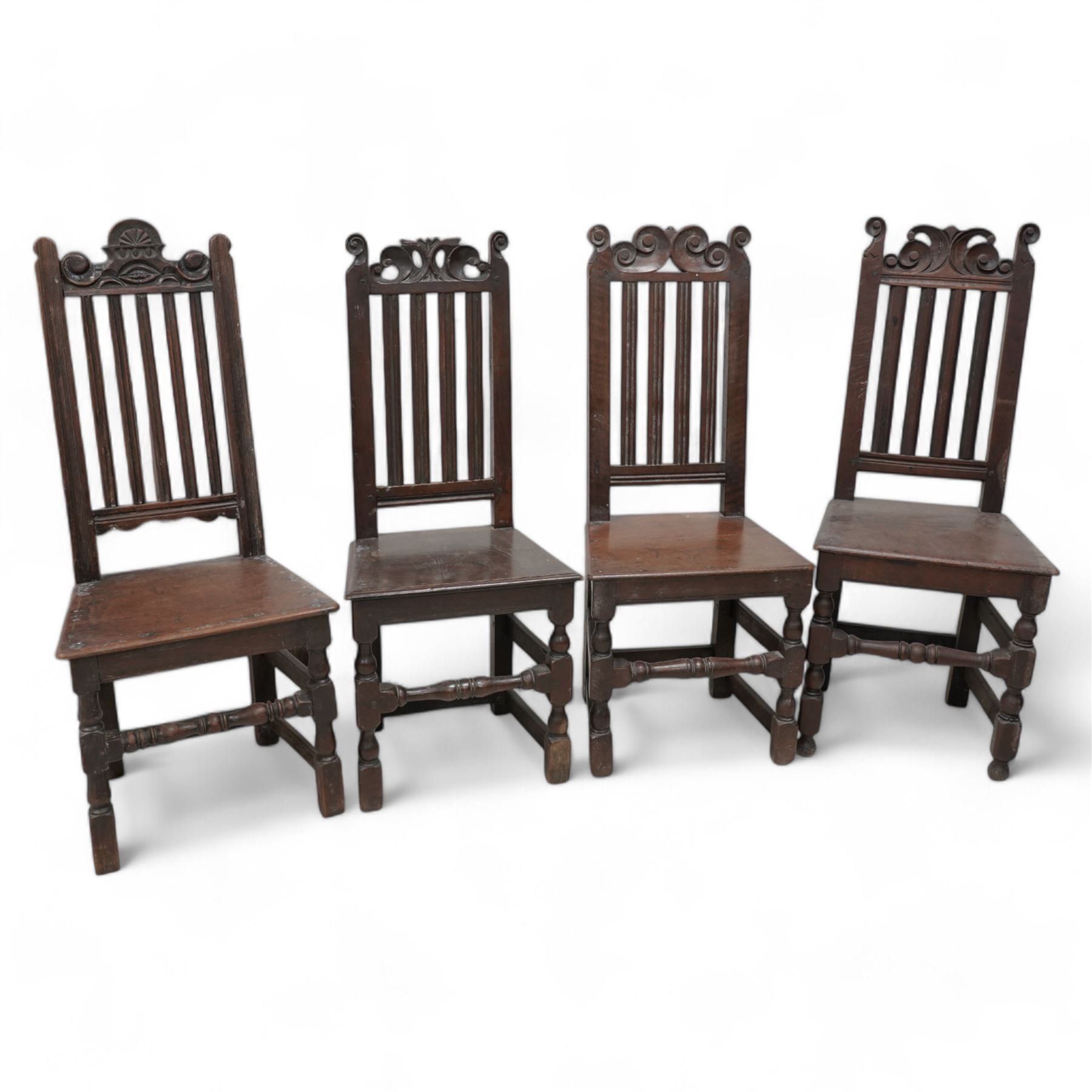 Mixed set of four 18th century oak side chairs, each with scroll carved pediment over vertical slat back, plank seat over turned and block supports