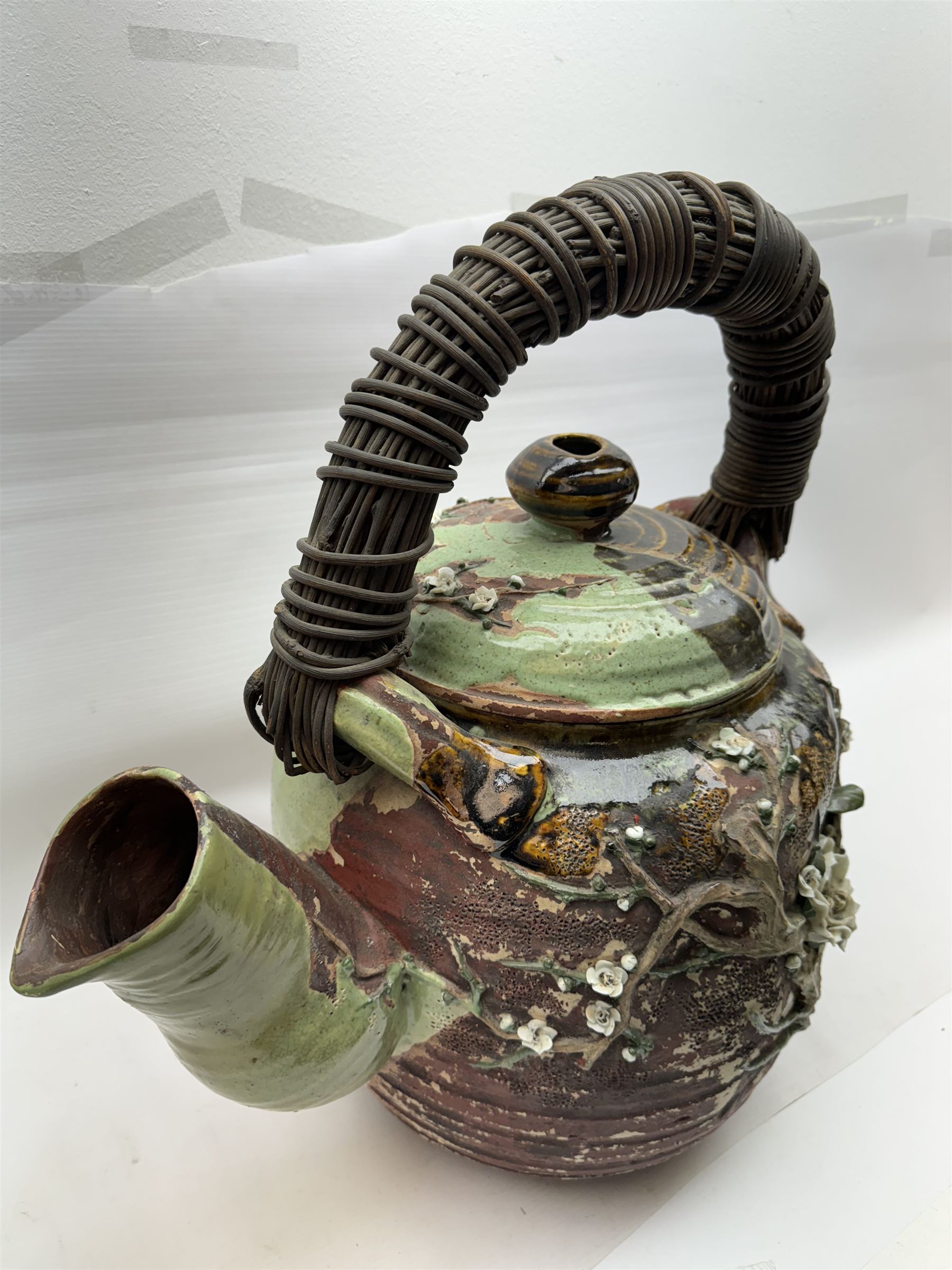 Very large Japanese Shigakari type coil built teapot, the body with a blossoming encrusted tree, woven loop handle and part green glazed spout and cover, H52cm