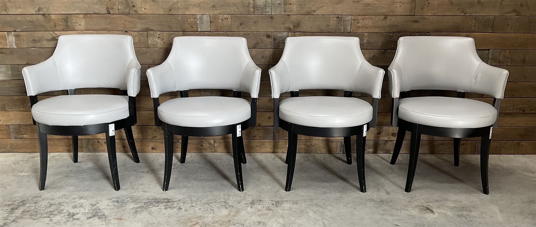 Four ebonised framed tub shaped armchairs, upholstered in grey fabric