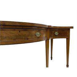 Large George III mahogany serpentine serving table, shaped top with crossing banding and stringing, the frieze fitted with three cock-beaded drawers, oval pressed brass handle plates decorated with urns, on square tapering supports with spade feet 