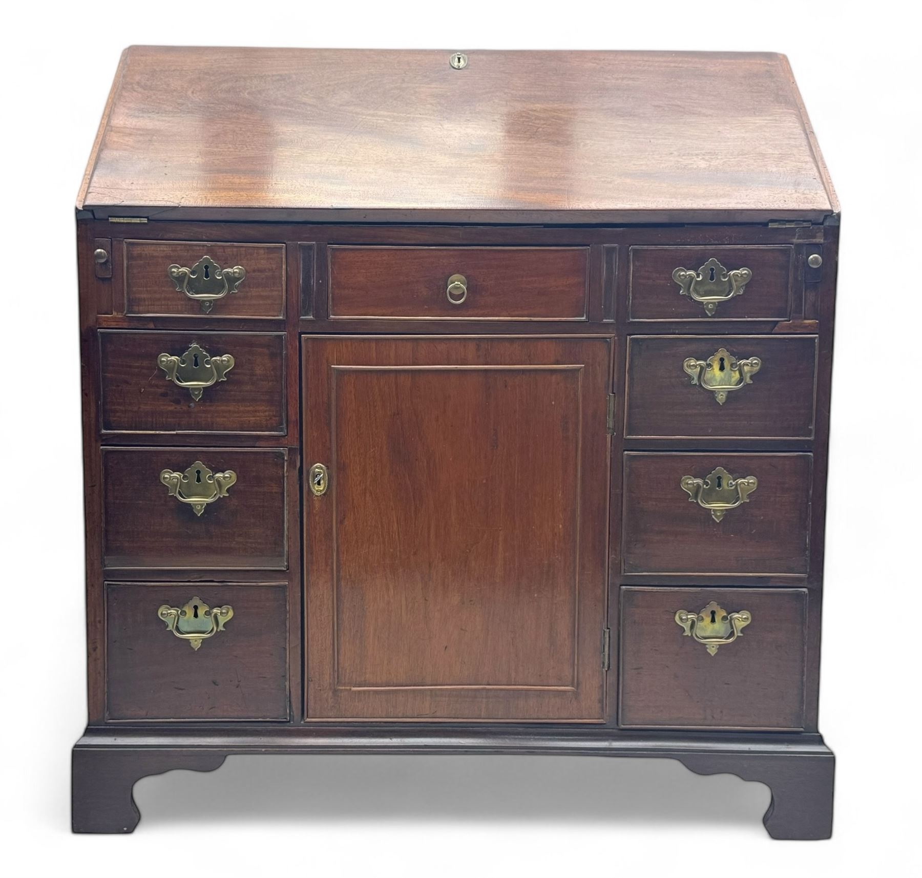 George III mahogany bureau, the fall-front enclosing fitted interior with pigeonholes and central cupboard, over an arrangement of nine short drawers surrounding a central cupboard, on shaped bracket feet