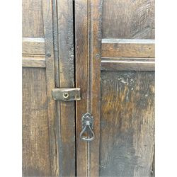 17th century and later oak hall cupboard, panelled front and sides with moulded frame, enclosed by single door with wrought metal hinges and handle, the interior fitted with hooks, on stile supports 