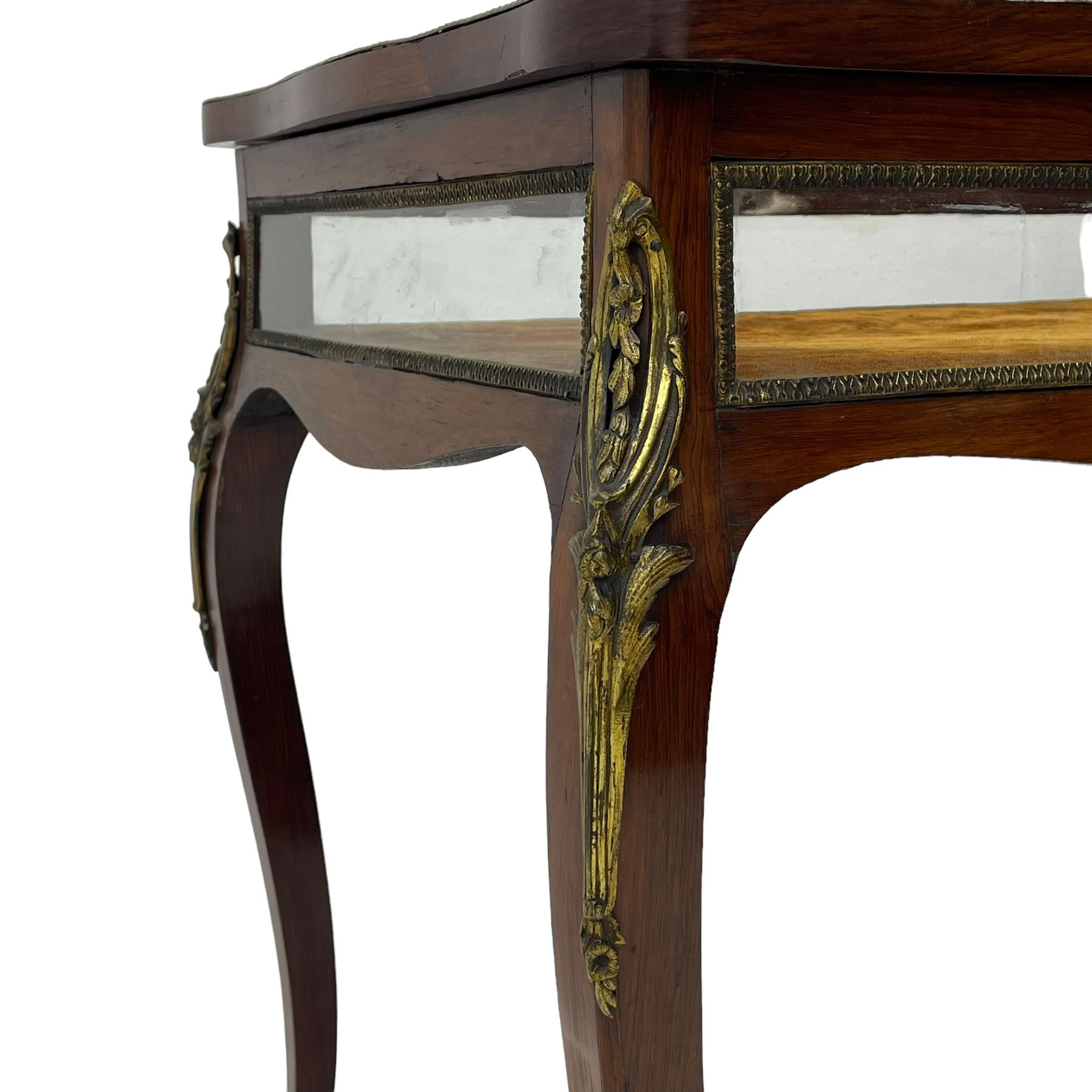 Victorian inlaid rosewood bijouterie table cabinet, shaped form, enclosed by hinged bevel glazed lid with shell and floral inlays, fabric lined interior, glazed sides within foliate cast gilt metal edging, on cabriole supports with floral cast gilt metal mounts and terminal caps 