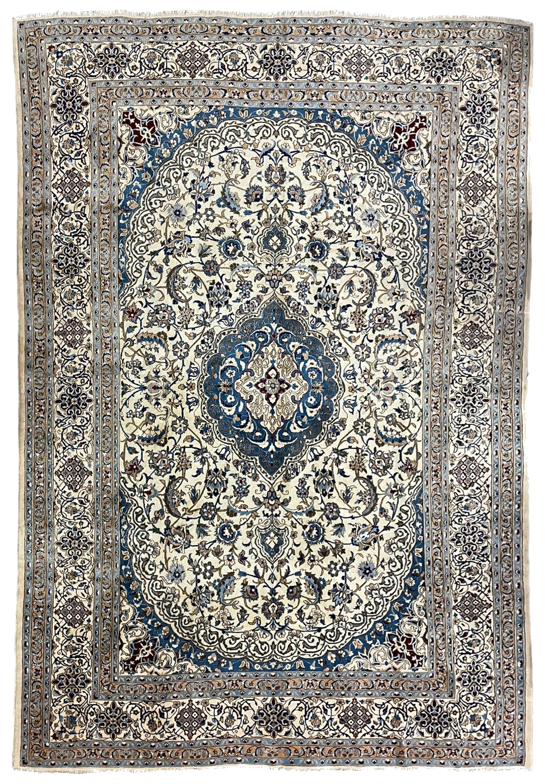 Persian Nain ivory ground carpet, the field decorated all over with leafy branches and stylised flower head motifs, blue ground central medallion and matching spandrels decorated with trailing foliate pattern, repeating guarded border with overall floral design