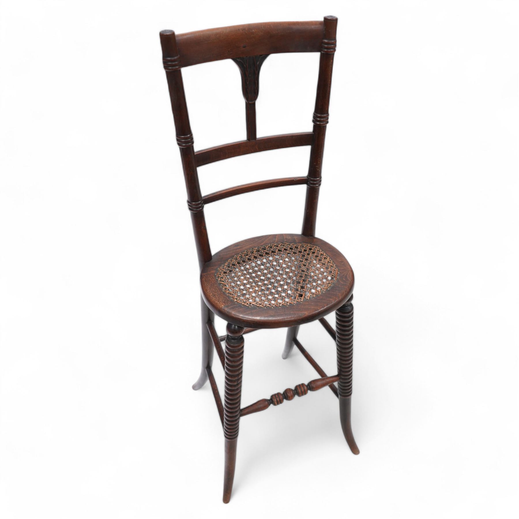 Regency beech framed child's correction chair, ring turned upright supports united by stretcher back carved with curled leaf motif, oval cane work seat, on rib turned supports terminating to splayed feet, united by turned stretchers 