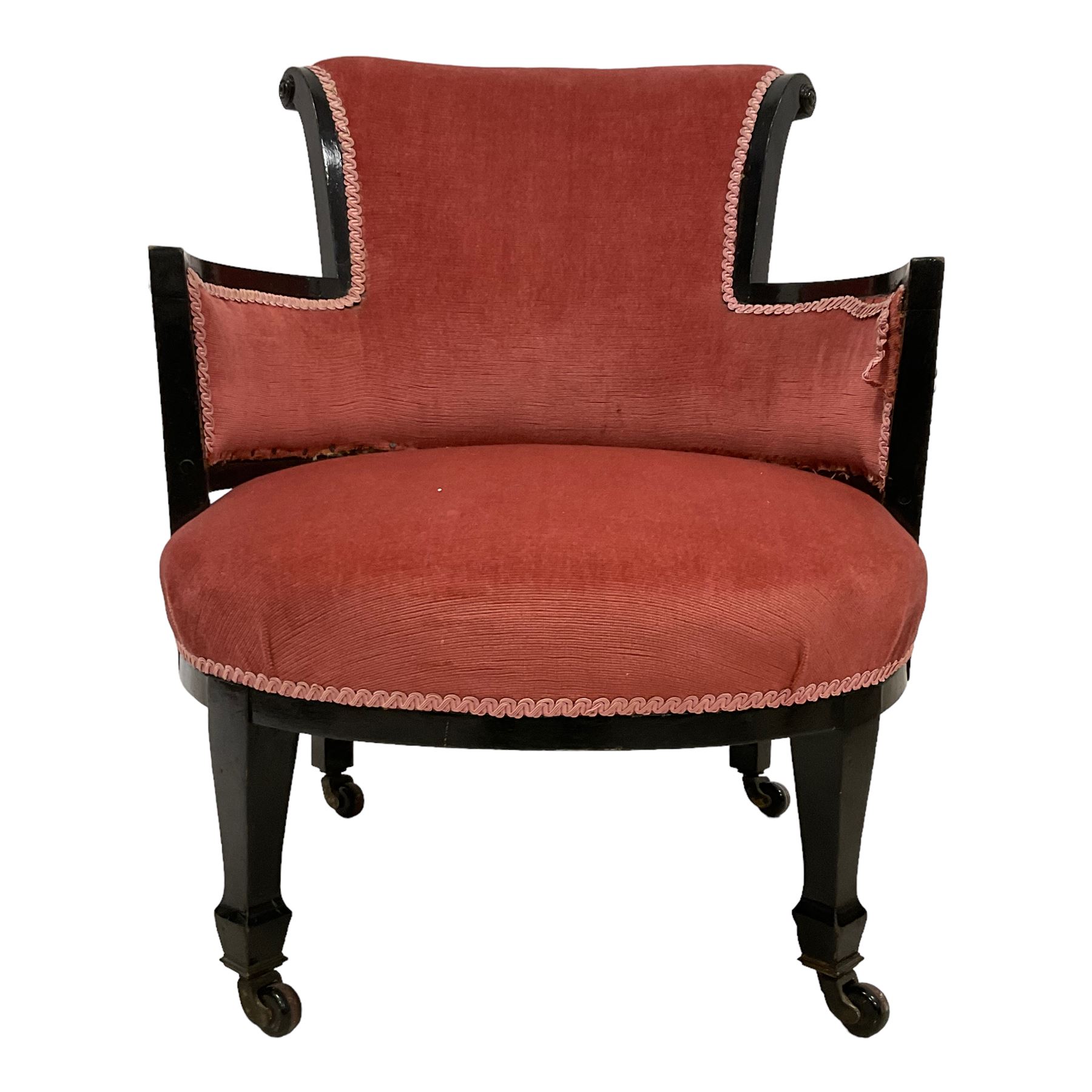 Early 20th century ebonised hardwood-framed armchair, rolled back and curved arms, upholstered in pink fabric, on square tapering front supports with spade feet, brass and ceramic castors 