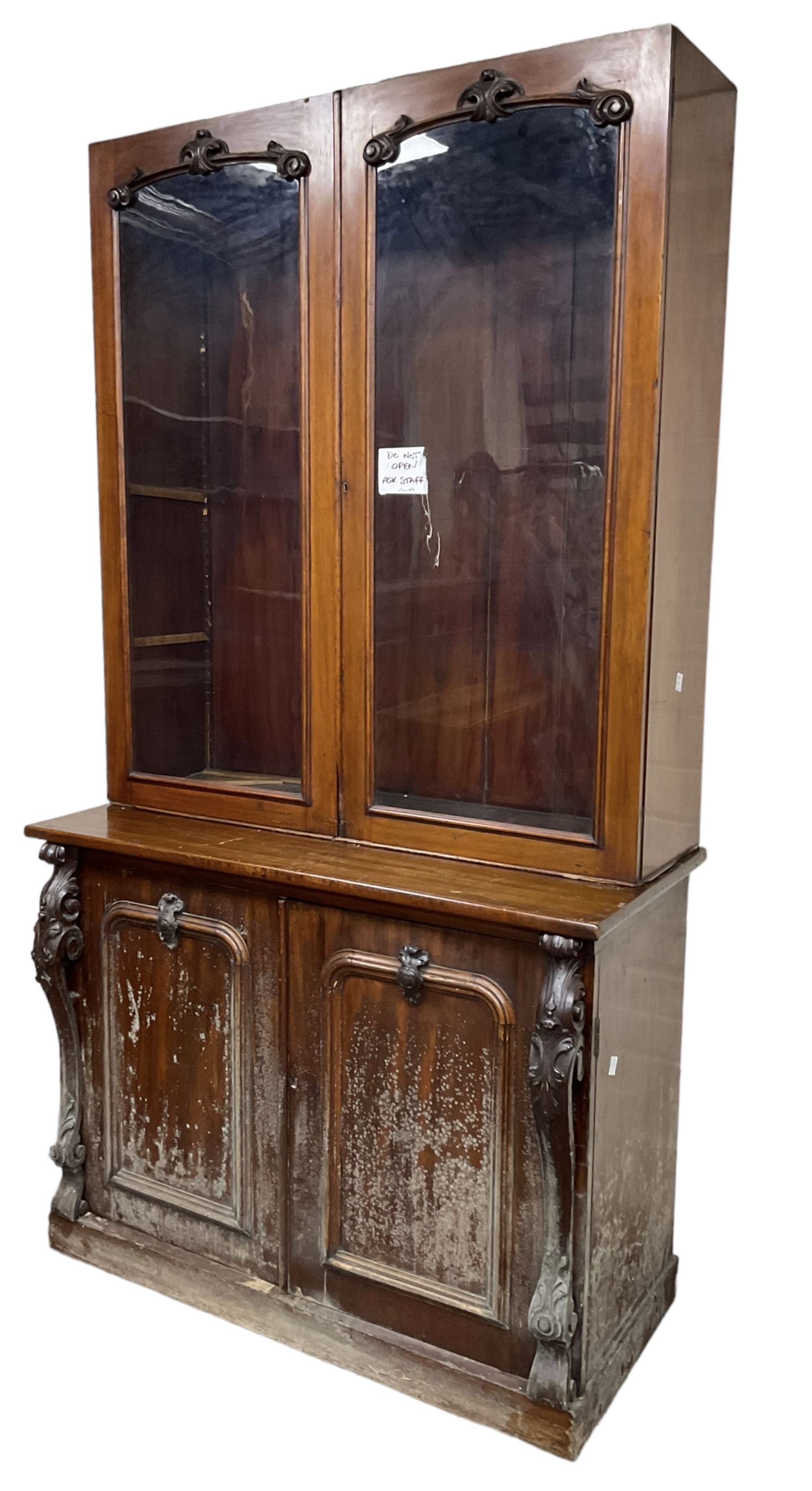 Victorian mahogany bookcase on cupboard, enclosed by two glazed doors, the base enclosed by two panelled doors flanked by acanthus carved upright pilasters, on plinth base