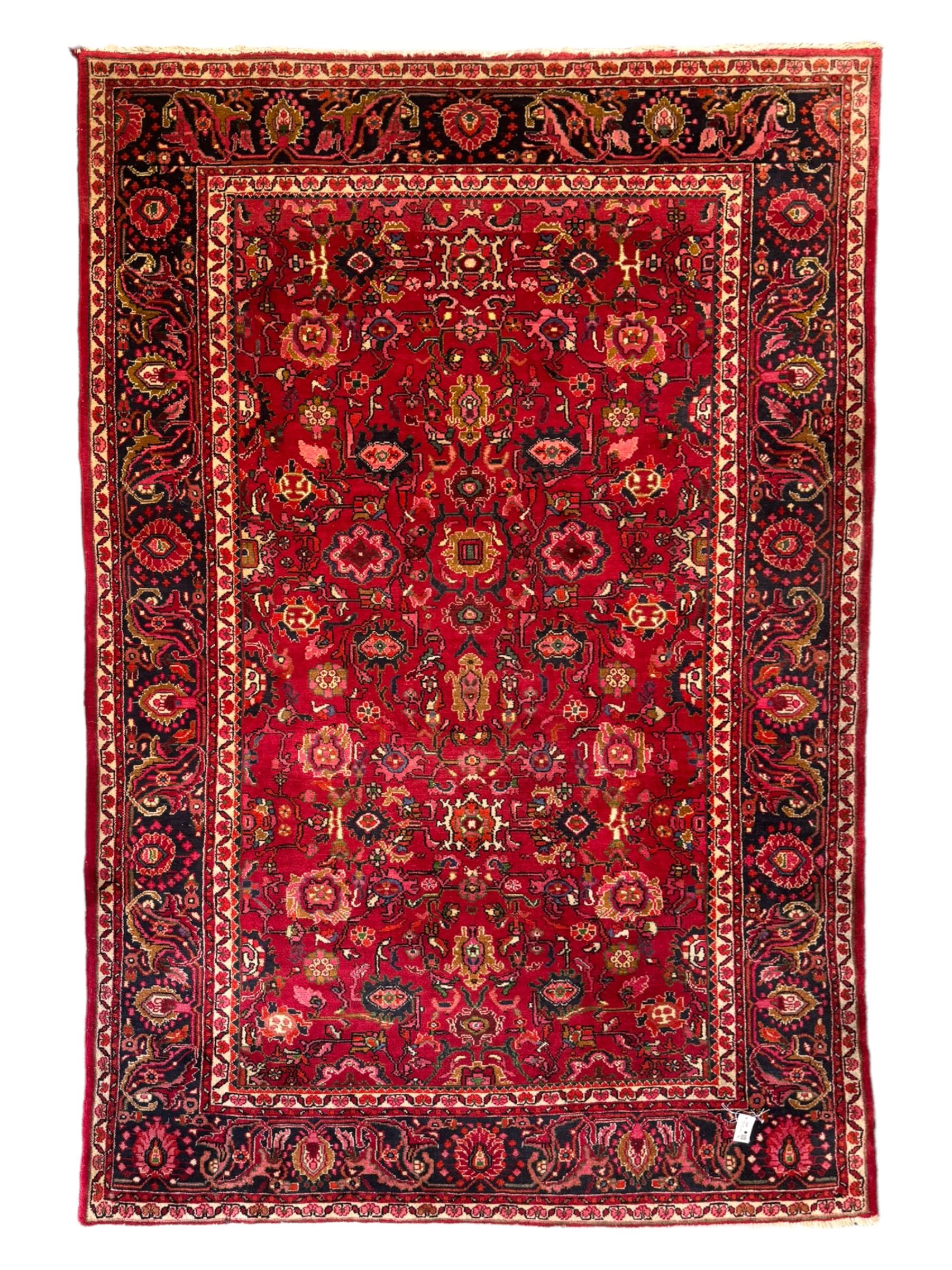 Persian Nanaj crimson ground carpet, the busy field filled with interconnecting stylised plant motifs with scrolling branches, the guarded indigo border decorated with repeating palmettes and foliate patterns