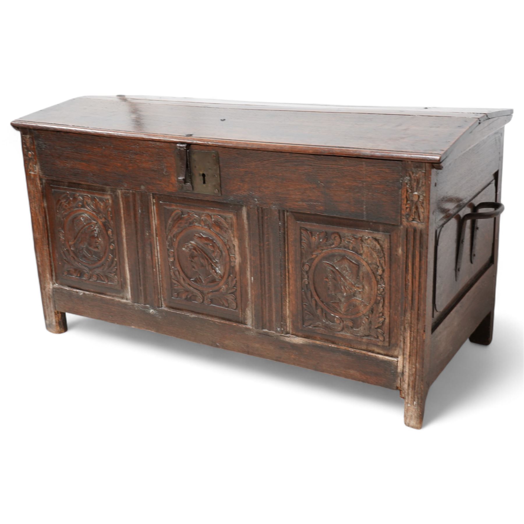 18th century carved oak coffer or chest, sloped hinged lid over panelled front, carved with three Northern European portraits with foliage surrounds decorated with birds, fitted with wrought metal carrying handles, on fluted stile supports 