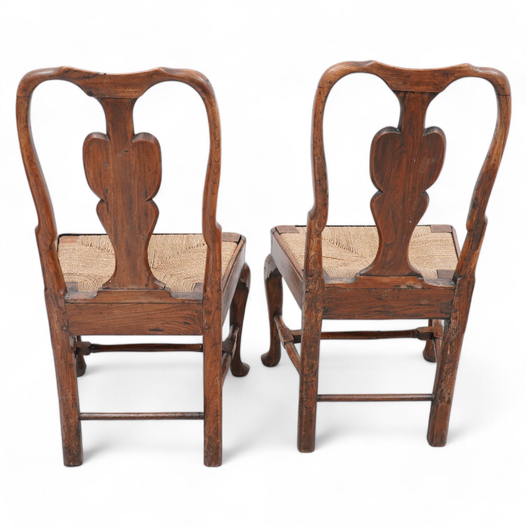 Pair of 18th century elm side chairs, shaped splat back over drop-in rush seat, on cabriole supports united by turned stretchers 