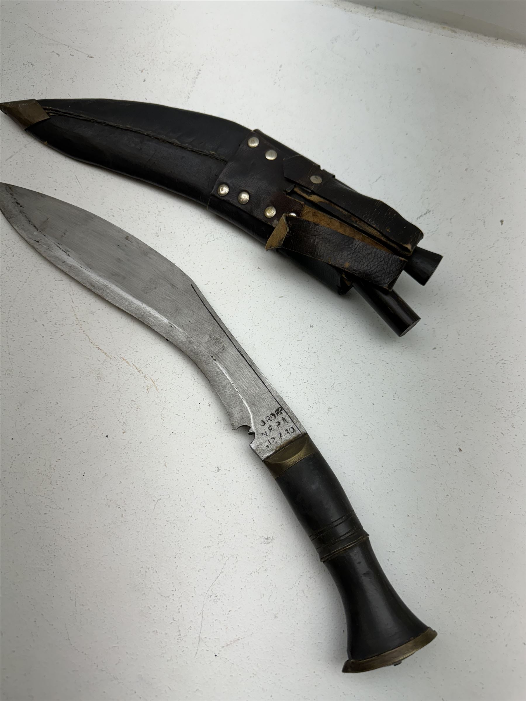 British Service issued Kukri, circa 1980s, with curving blade, hardwood and brass grip in leather covered scabbard with two skinning knives, blade, stamped 12th  December 1980 Dharan Nepal to blade, blade L28cm, overall L39cm