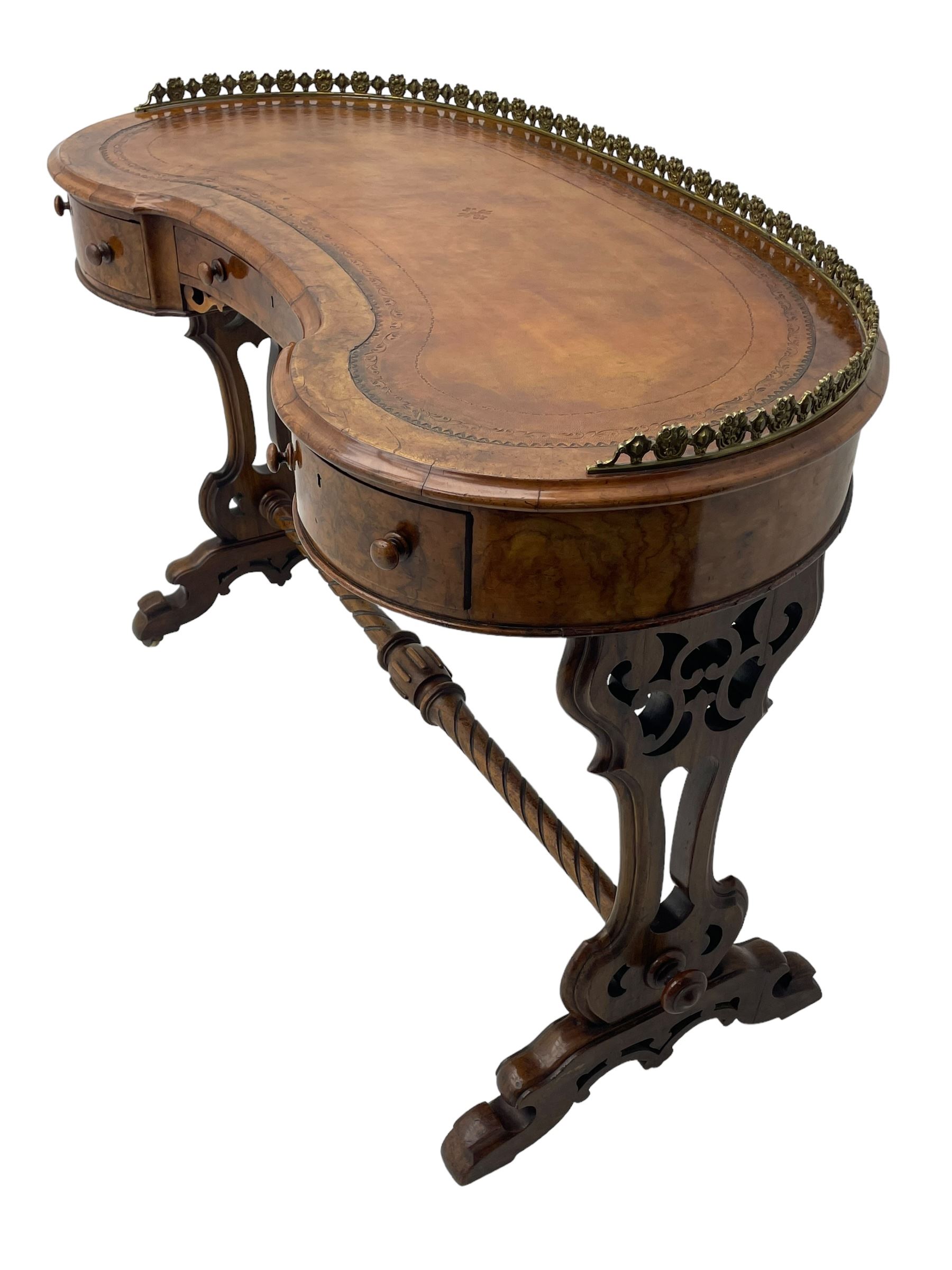 Victorian walnut kidney-shaped writing desk, moulded top with floral cast brass gallery and inset leather writing surface, fitted with three frieze drawers with turned handles, shaped and pierced end supports on raised platforms terminating to splayed feet, united by twist turned and lobe carved stretcher, brass and ceramic castors 