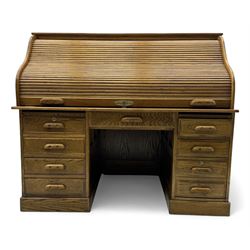 Early 20th century oak tambour roll-top desk, the top with fitted interior including drawers, pigeonholes and compartments, the twin pedestals fitted with four drawers with carved handles, supported by plinth base 