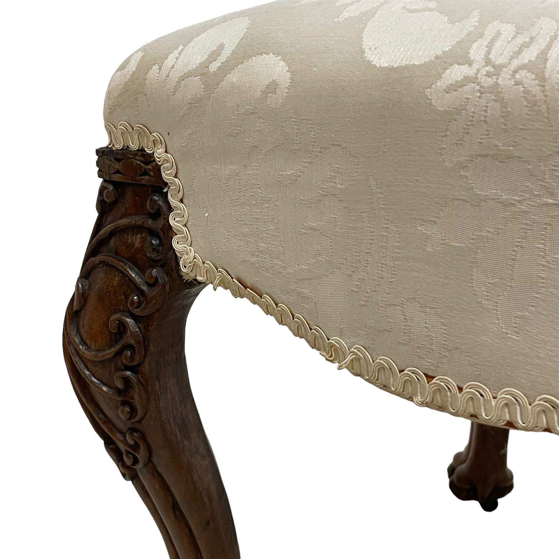 Georgian Irish mahogany dressing stool, overstuffed seat upholstered in in ivory damask fabric, the cabriole supports decorated with moulded interlacing scroll motifs with mycelium cap detail, over lobe carvings terminating to large paw feet