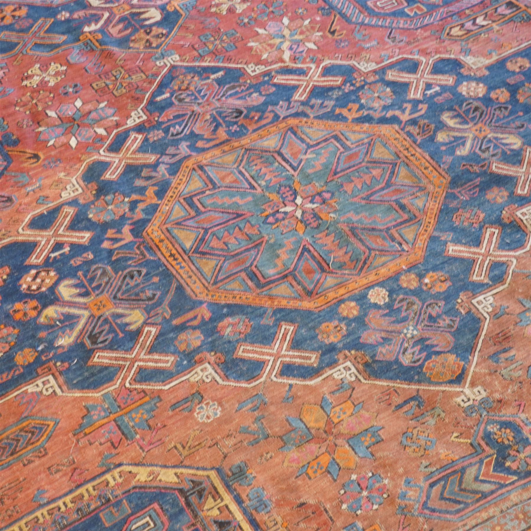 Old Persian red ground flat woven carpet, the field with three large medallions surrounded by small stylised flower head motifs, geometric border enclosed within running water band 346