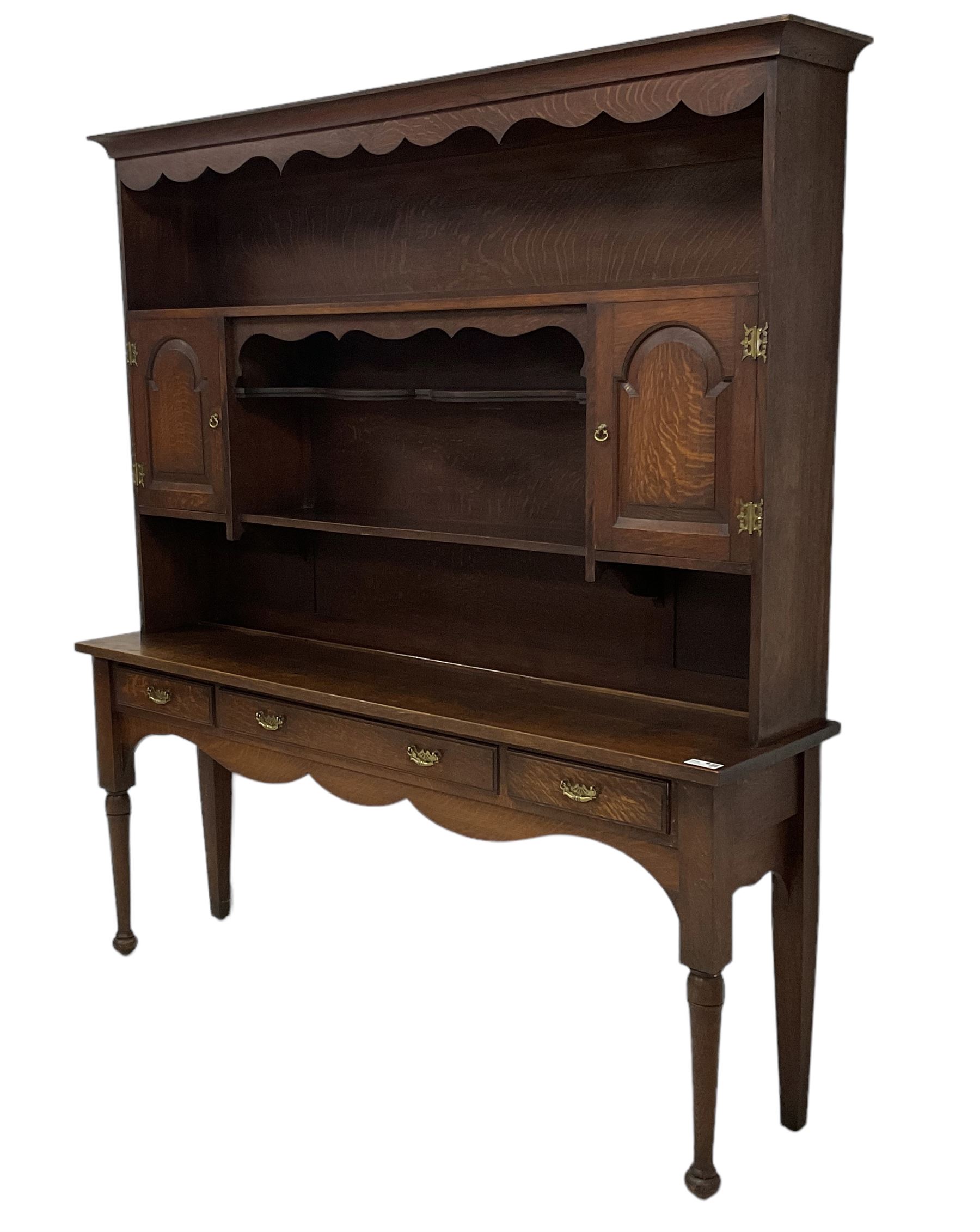 Early 20th century Georgian design oak dresser, projecting cornice with shaped apron over a three-tier plate rack with flanking fielded spice cupboards, the base fitted with three drawers, on turned supports