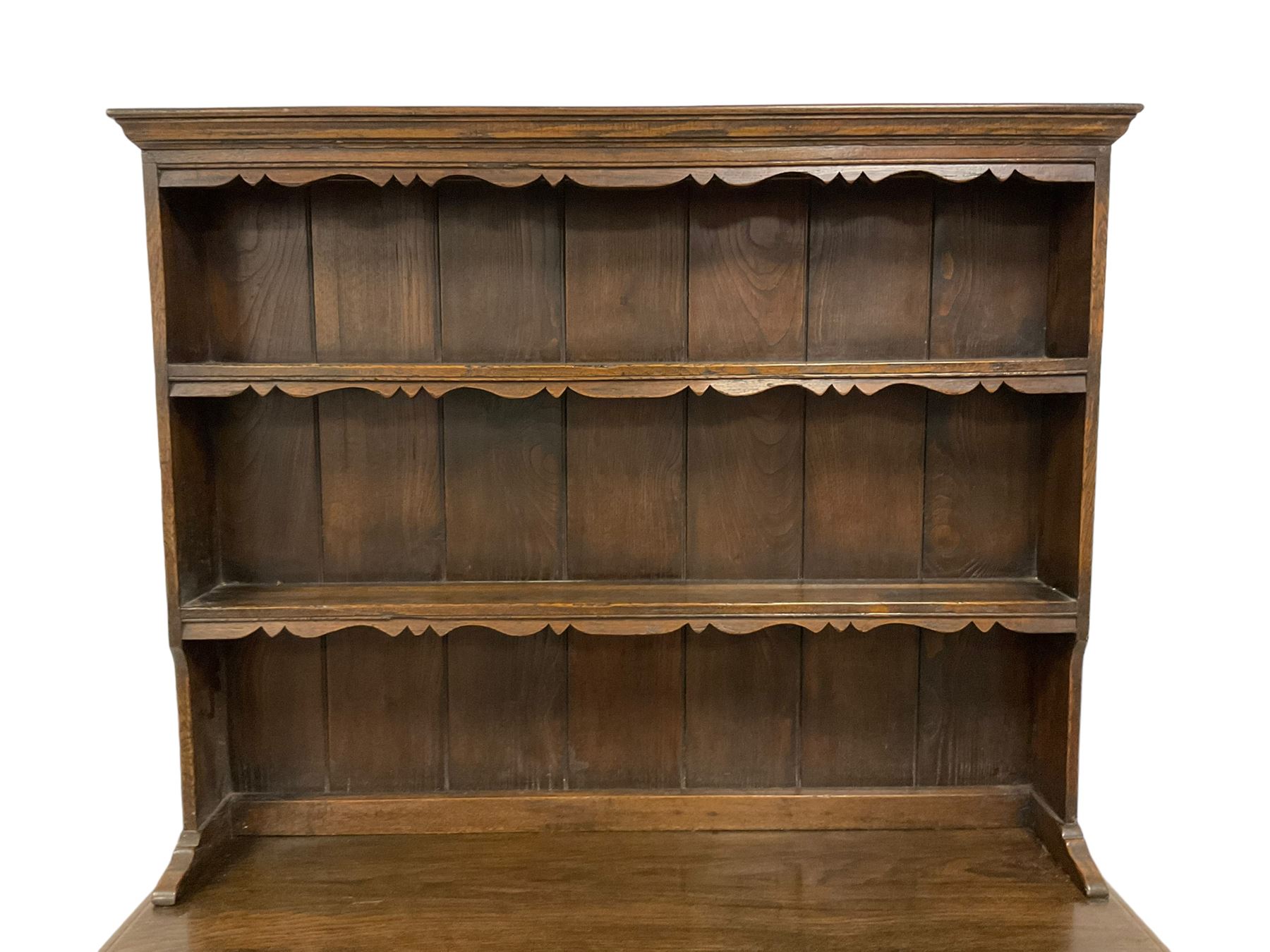 Georgian design oak dresser, two-tier plate rack with shaped aprons, the base fitted with two fielded moulded drawers, over two panelled cupboards carved with scrolling acanthus leaves, with guilloche carved central upright, on stile feet