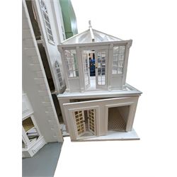 Large three storey modern dolls house, painted white with latticed windows, grey roof and metal fencing, with decorated interior, together with two dolls house garden rooms and two conservatories