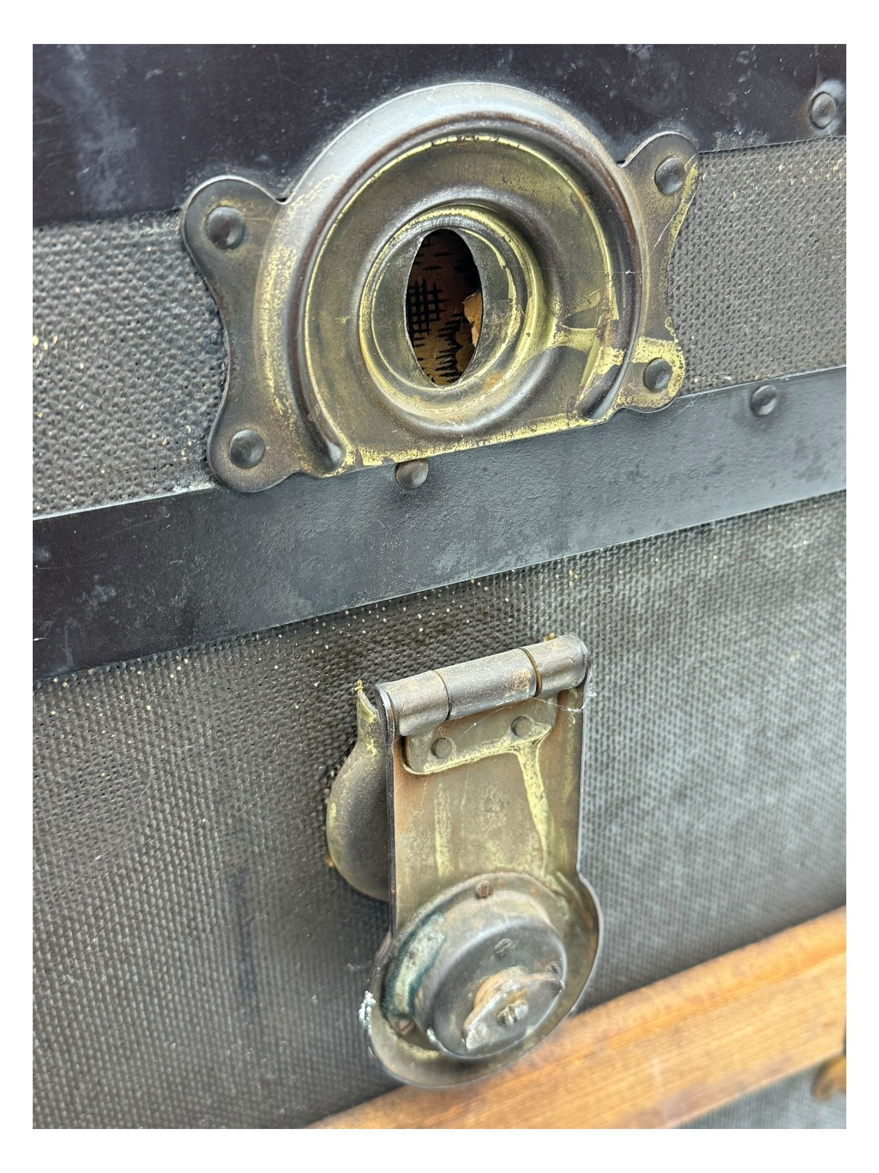 Early 20th century 'McBrine Baggage' steamer trunk, oak frame and black canvas covering, featuring metal hardware and leather straps, fitted with central lock, additional latches, and corner protectors, the interior is lined with floral-patterned paper and includes a removable top tray with makers label 