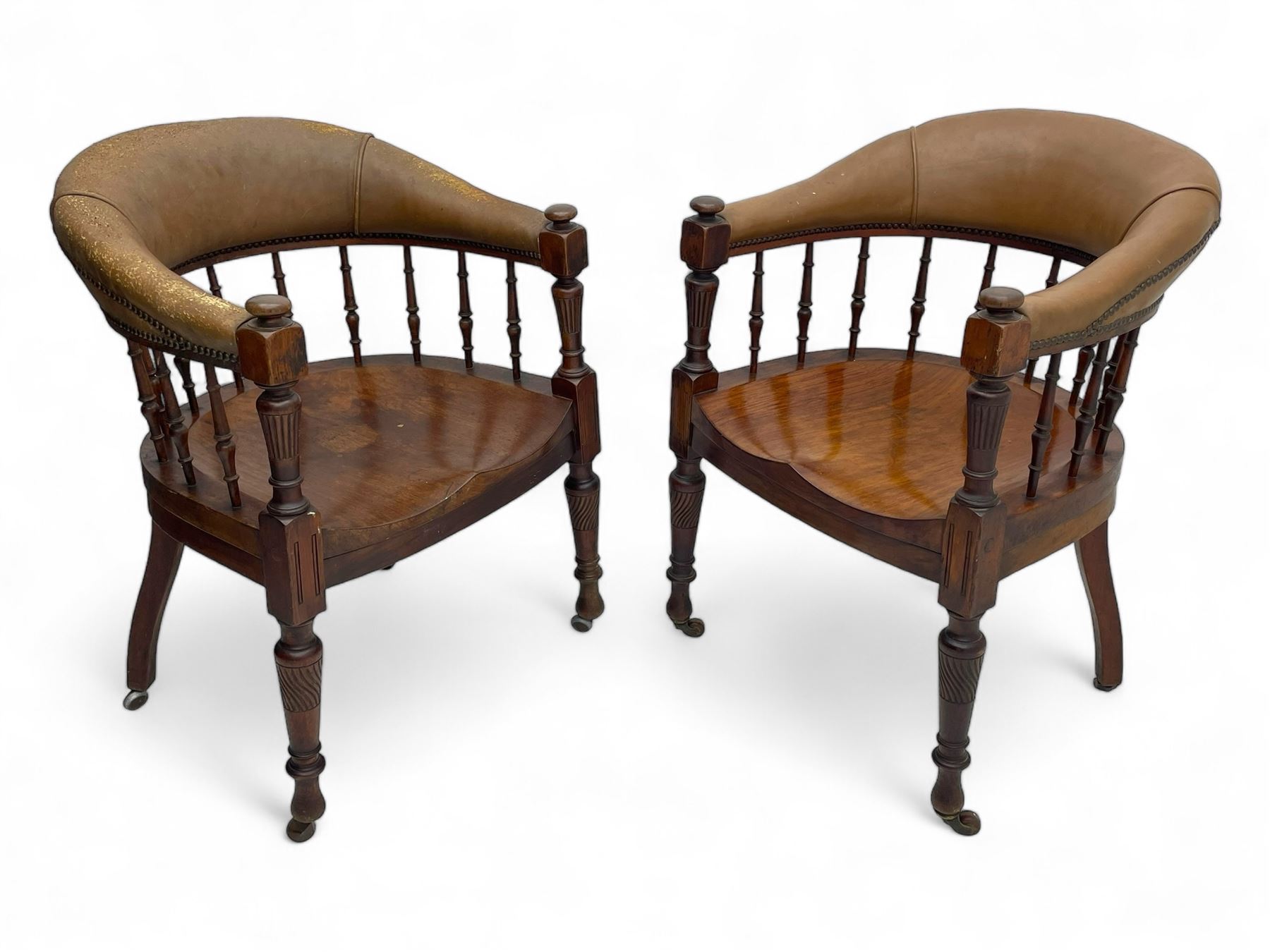 Pair of late Victorian walnut tub-shaped elbow chairs, the cushioned cresting rail upholstered in leather on spindle turned supports, dished saddle seat on turned supports