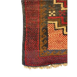 Baluchi crimson ground rug, the central field decorated with two stacked geometric lozenge medallions, surrounded by stepped multicoloured motifs, the wide border with alternating angular motifs in deep red, within a narrow brown guard stripe