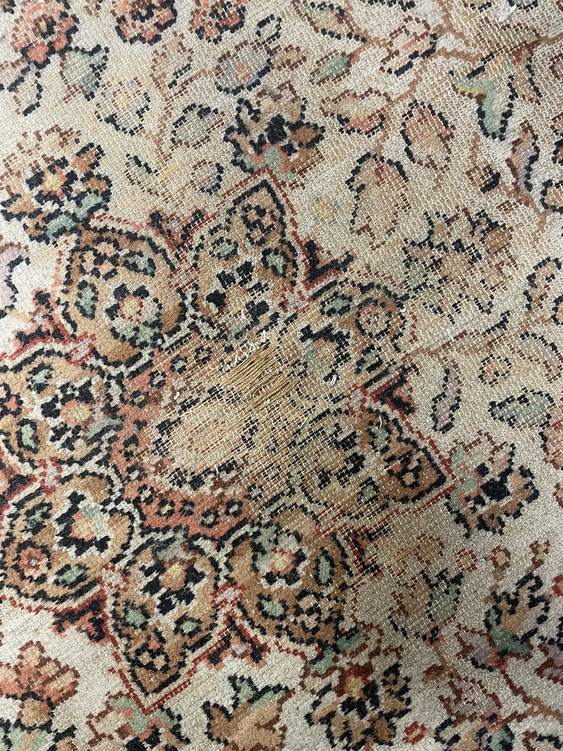 Large Persian design carpet, overall floral design, the field decorated with large rosette motifs surrounded by trailing foliate motifs, the border decorated with trailing branch and stylised plant motifs