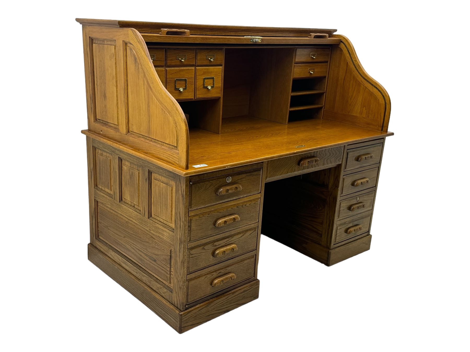 Early 20th century oak tambour roll-top desk, the top with fitted interior including drawers, pigeonholes and compartments, the twin pedestals fitted with four drawers with carved handles, supported by plinth base 