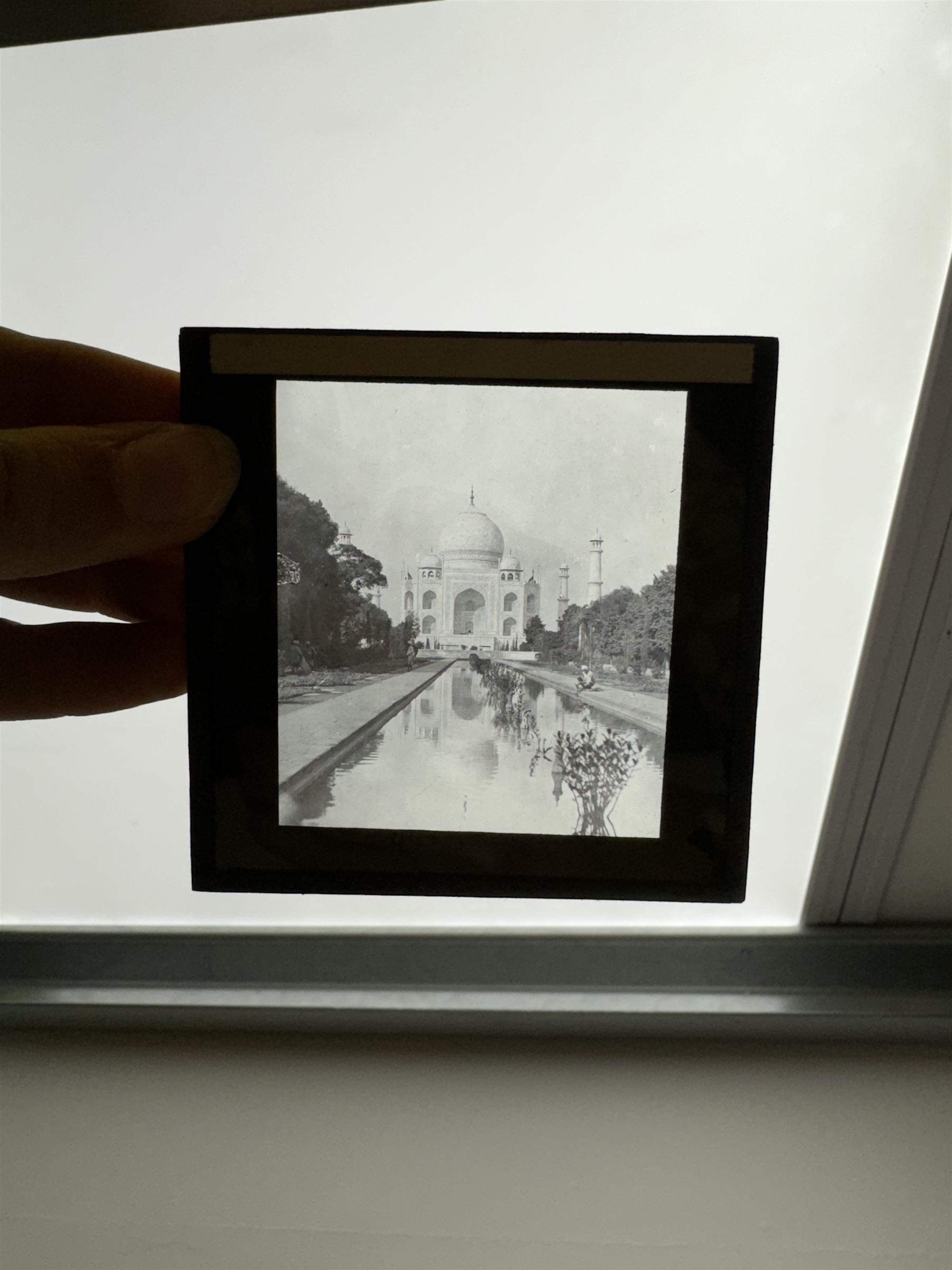 Collection of magic lantern slides, predominantly depicting views of India, with scenes including including the Taj Mahal, tombs, monuments, street scenes, people and animals, in compartmentalised wooden case 