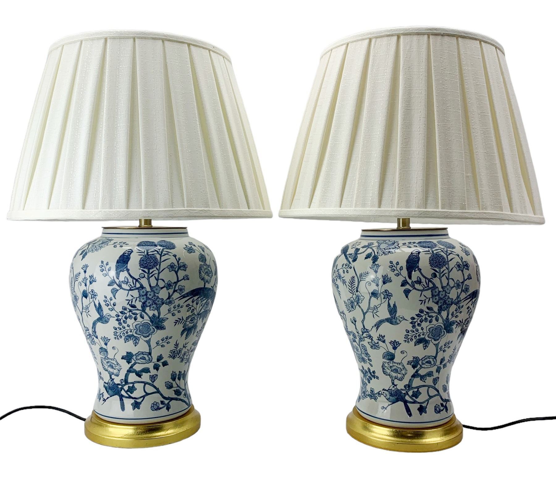 Pair of blue and white table lamps, each of inverted baluster form, decorated with exotic birds, raised upon circular gilt bases, H39cm excluding fitting