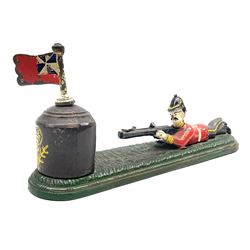 Very rare 19th century John Harper & Co. mechanical cast-iron money box, registered number 33821 patented 1885, inscribed on metal plaque 'Wimbledon Bank', based on the Queen's Trophy for shooting at Wimbledon, depicting a British Infantry man in red tunic and blue trousers lying on the ground using a gun to fire a brass coin launcher into a pill box with removable moving flag above L30cm