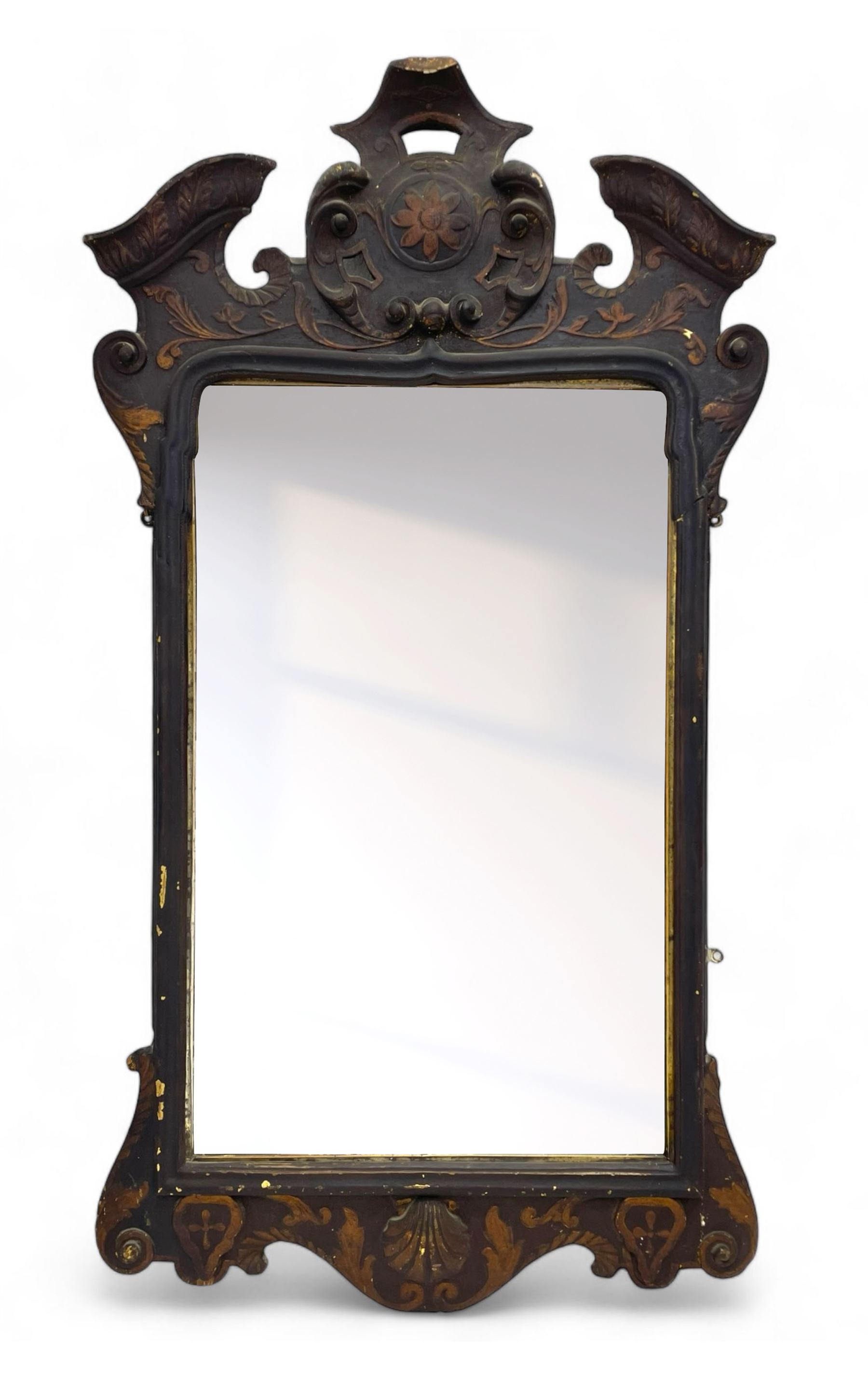 18th century black lacquered and gilt wall mirror, broken arch pediment with central cartouche decorated with curled leaves and foliate motifs, scrolled acanthus leaf eared brackets, bevelled mirror plate within gilt slip and moulded outer frame, lower shell motif surrounded by curled acanthus leaves and shield motifs 