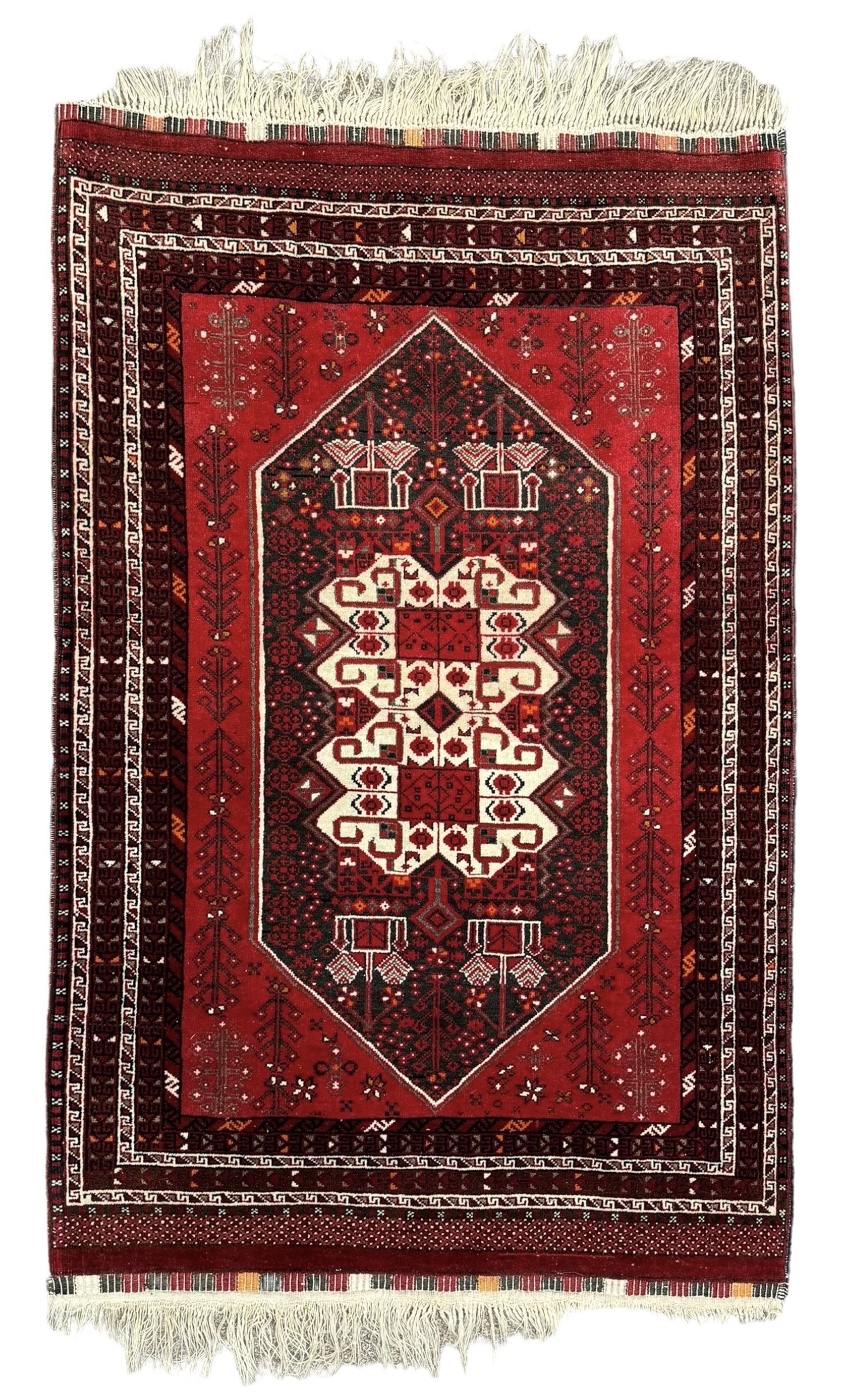 Persian Heriz red ground rug, the field with three large central medallions in indigo and ivory, border with geometric pattern within multiple guard stripes (119cm x 189cm); Persian Yomut crimson ground rug, central field with ivory medallion with geometric motifs, main border with geometric pattern within multiple guard stripes (88cm x 133cm)