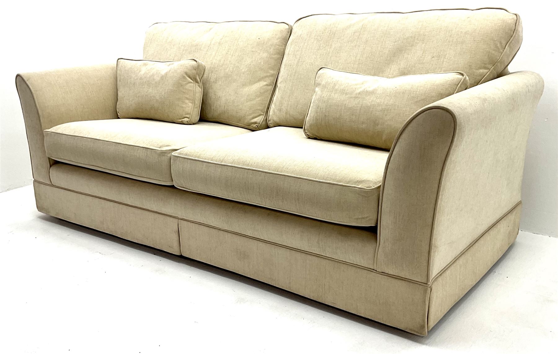 Large three seat sofa upholstered in cream fabric, castors 