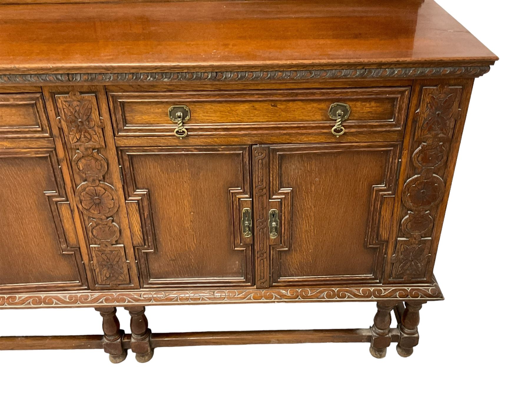 Early 20th century oak sideboard, raised panelled back with foliate carved decoration, rectangular top with gadrooned edge, fitted with two drawers over cupboards with field moulded facias, turned supports joined by stretchers