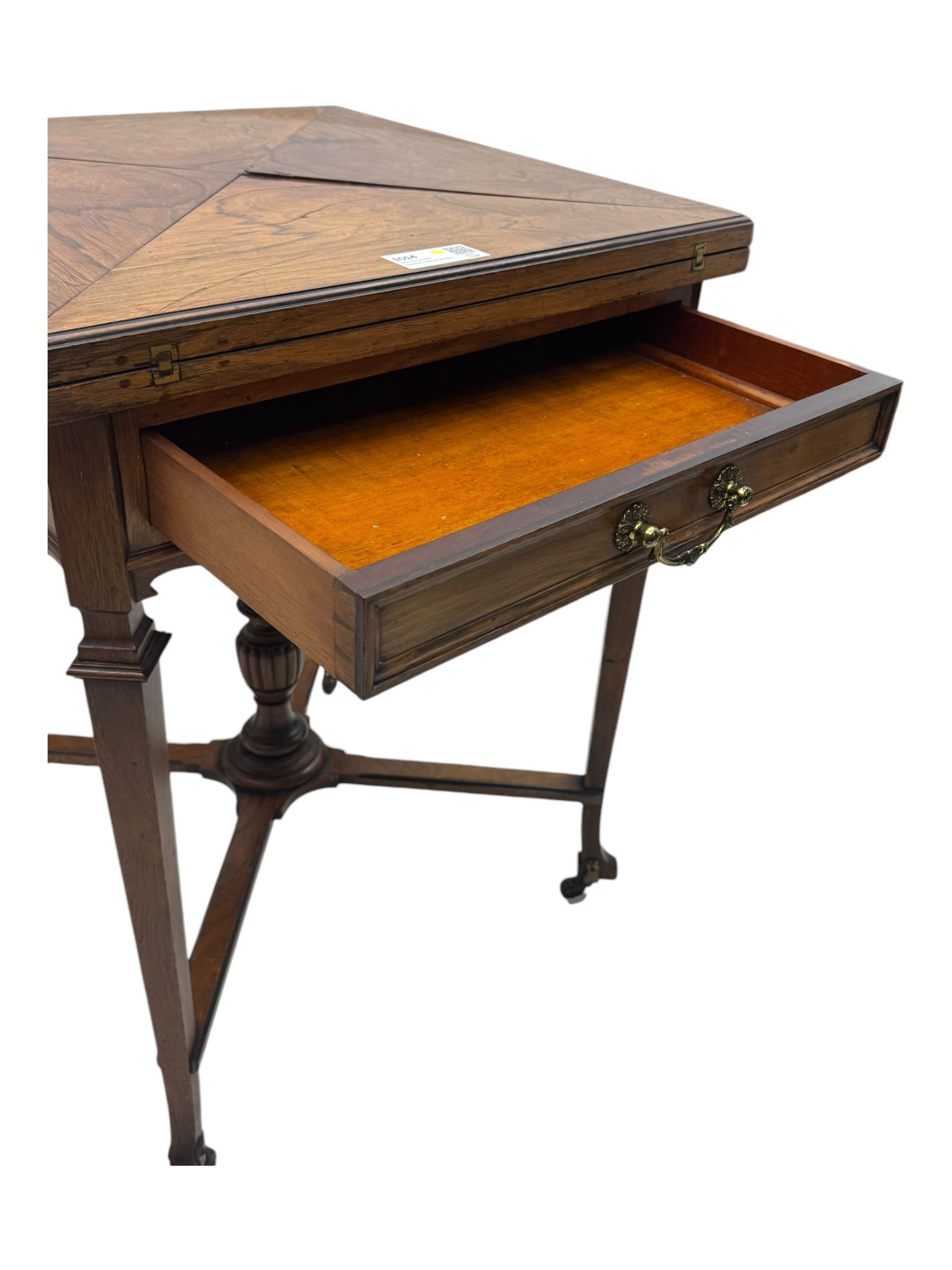 Victorian rosewood envelope games table, the moulded square top with four triangular hinged leaves, revealing inset baize playing surface and sunken counter wells, fitted with single frieze drawer, on square tapering supports united by x-framed stretchers and turned central column, on brass and ceramic castors 