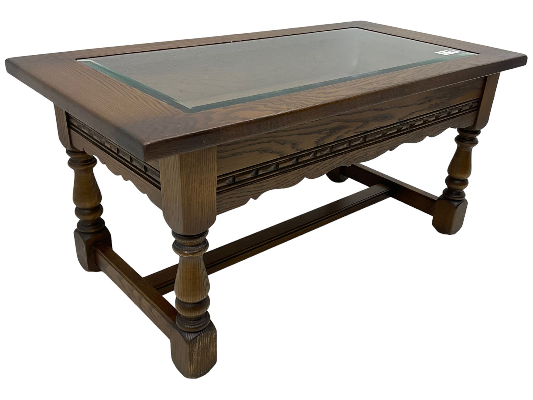 Old Charm - oak coffee table, rectangular top with glass inset over carved scalloped apron, on turned square supports connected by H-stretcher