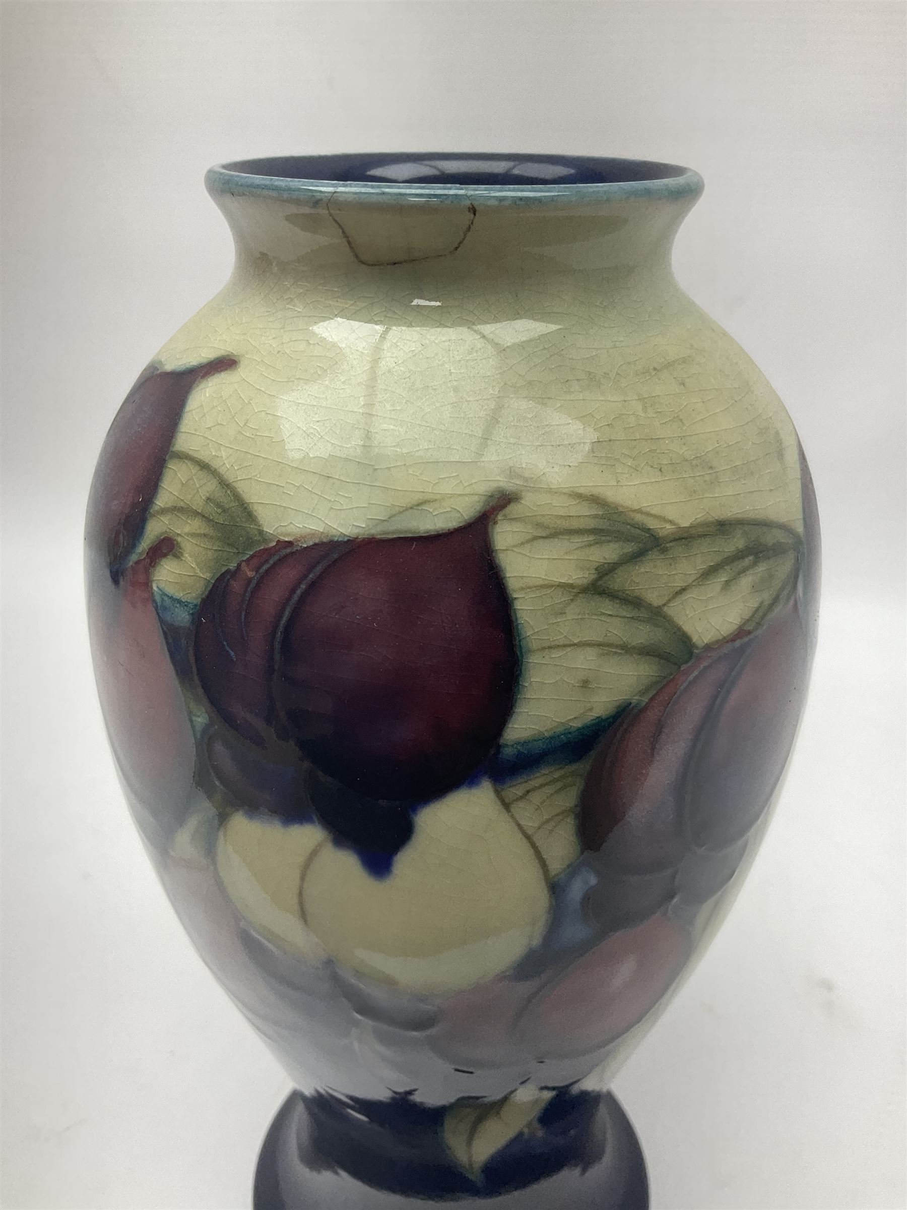 Moorcroft Wisteria pattern vase, circa 1916, lender baluster form, decorated with foliage, in tones of creams and purples, on a blue ground, with painted and impressed sign beneath, H23cm