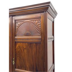 Late Victorian walnut triple wardrobe, projecting moulded cornice over central bevelled mirror door and flanking panelled doors, the top panels carved with fluted fans and stylised leaf motifs, the interior fitted with three linen slides, two drawers and hanging space, two long drawers to base, reed moulded uprights and vertical fluted horizontal rails 