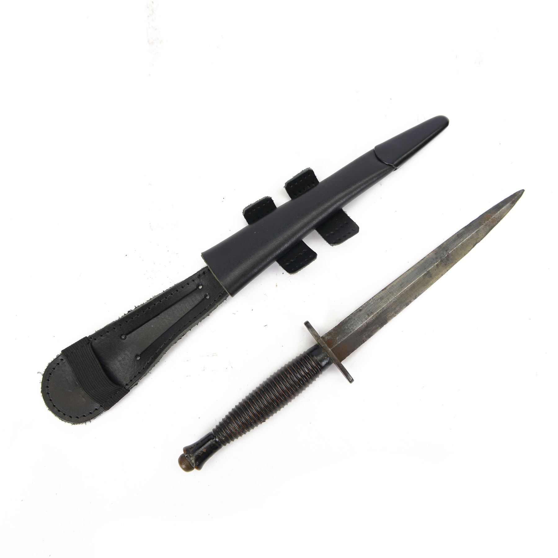 British commando knife, with ribbed ebonised steel hilt with a blued stiletto blade marked, with leather scabbard, blade 18cm