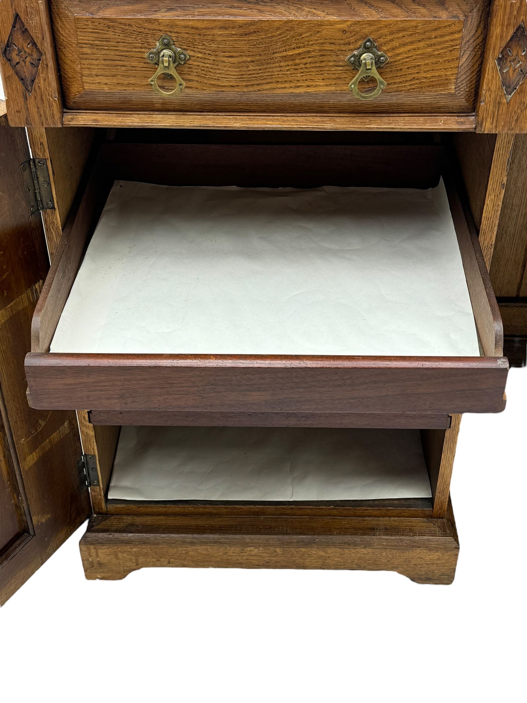 Late Victorian oak twin pedestal desk, chamfered rectangular top over three convex front edge drawers and two panelled cupboards, flanked by carved supports with roundels and diamond motif, on bracketed plinth base