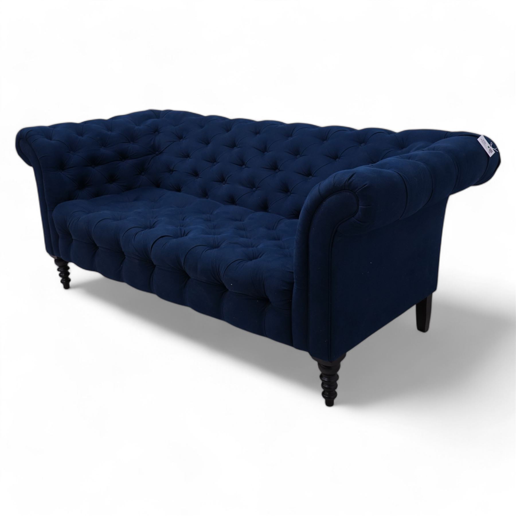 Chesterfield two-seat sofa, traditional shape with rolled arms, upholstered in deep blue buttoned fabric, on black finish turned front feet 