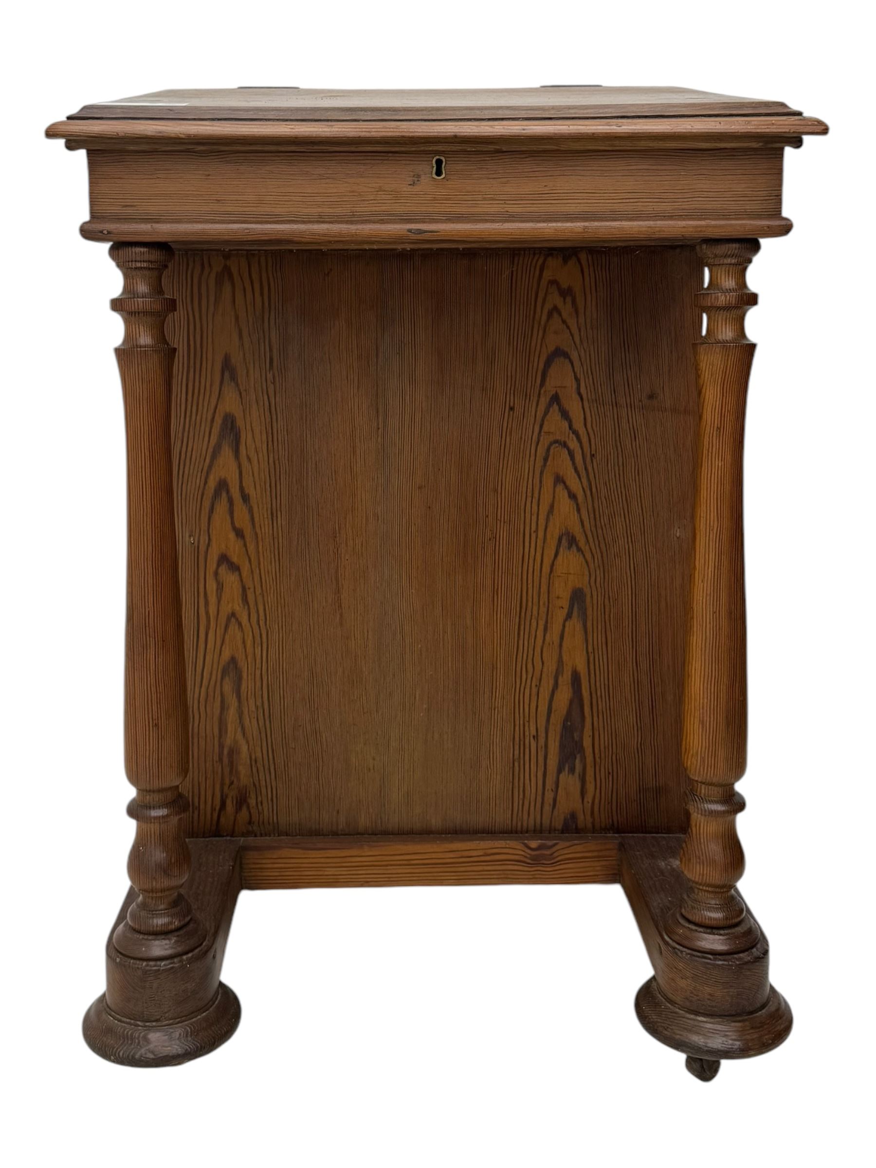 19th century pitch pine Davenport desk, sloping hinged top, fitted with four drawers, on turned column supports, turned compressed feet with castors 