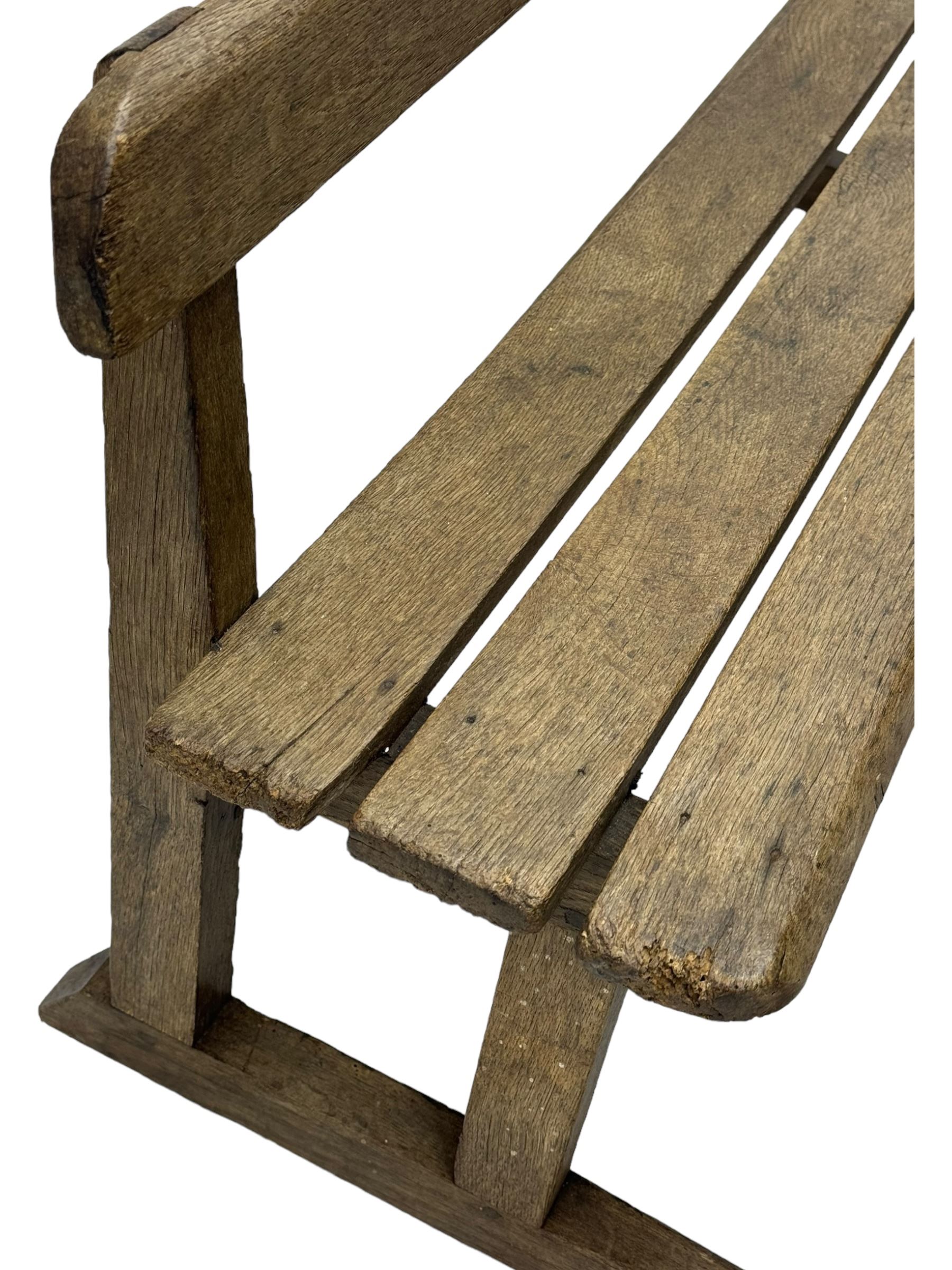 Victorian child's pine double school desk, the writing surface with two inkwells and two shelves underneath, integrated slatted bench seat raised on supports united by stretcher 