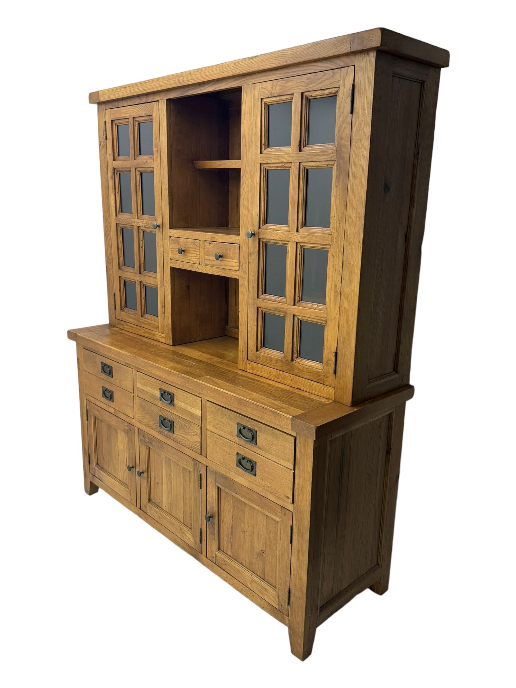 Oak dresser, upper section with twin glazed cupboard doors and central shelving with two trinket drawers, lower section fitted with six drawers over three panelled cupboard doors, raised on shaped feet 