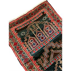 Baluchi dark indigo and crimson ground rug, decorated with cityscape within geometric border 