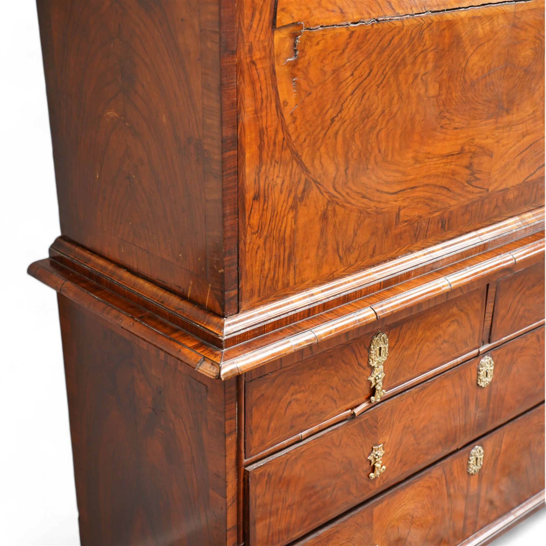 George II figured walnut escritoire, projecting moulded cornice over cavetto frieze with drawer, figured fall front revealing pigeonholes, a combination of drawers, central double cupboard and hidden drawers, fitted with two short and two long drawers, cast gilt metal escutcheons and drop handles, on turned feet 